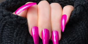 Unhas Stiletto. Foto mão com unhas compridas e pontudas e esmalte rosa