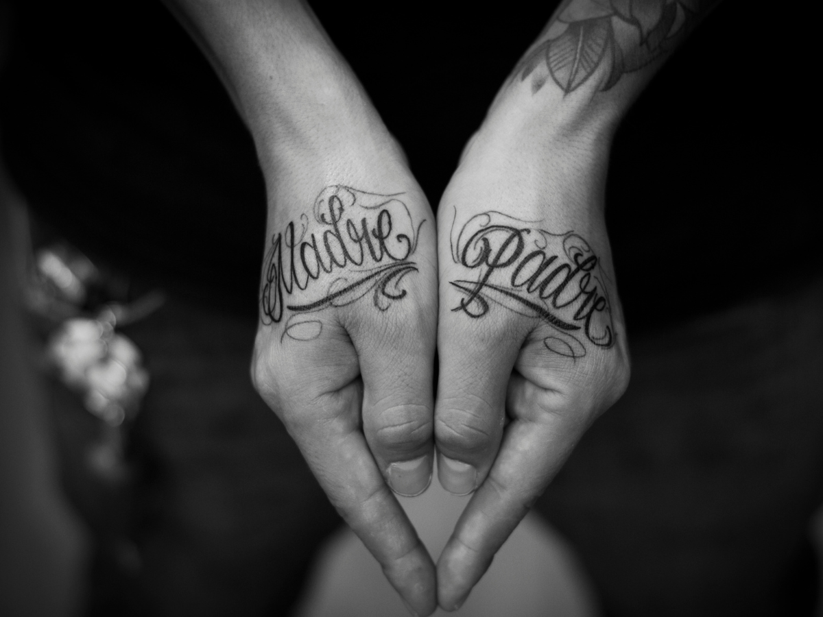 Ideais de tatuagens para homenagear a família. Foto mãos tatuadas com os nomes de madre e padre