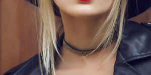 Gargantilha e chocker. Foto mostra uma mulher loira usando gargantilha preta com pedrinhas no pescoço.