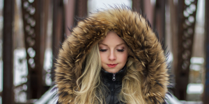 Manter os fios saudáveis no inverno. Foto mostra uma mulher com toca de pele protegendo os cabelos loiros do frio.