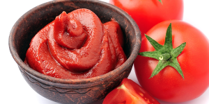 Reduzir as olheiras com tomate. Foto mostra um três tomates, sendo dois inteiros, um cortado e uma pasta de tomate em um pote