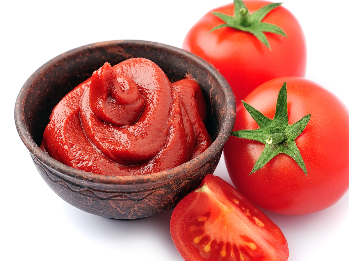 Reduzir as olheiras com tomate. Foto mostra um três tomates, sendo dois inteiros, um cortado e uma pasta de tomate em um pote