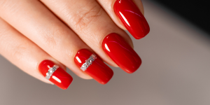 Unhas tendências para inverno 2023. Foto mostra unhas pintadas de vermelho e detalhes em prata