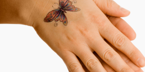Tatuagens delicadas para mulheres com 50 anos. Foto aparece uma mão com uma tatuagem de borboleta vermelha