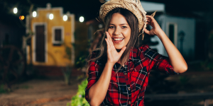 Looks de festa junina. Foto mulher com blusa xadrez vermelha e chapéu de palha