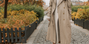 Trench Coat Feminino. Foto mostra uma mulher com o casaco comprido de cor bege