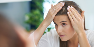 Scalp Care. Foto traz uma mulher em frente ao espelho olhando o couro cabeludo.