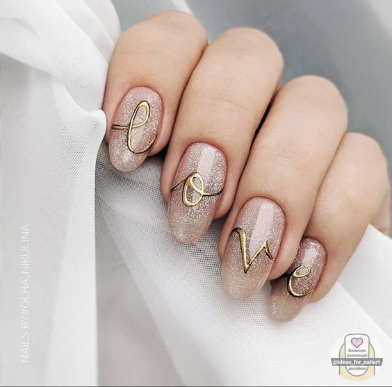 unhas almond decoradas com esmalte nude e letras desenhadas escrito love