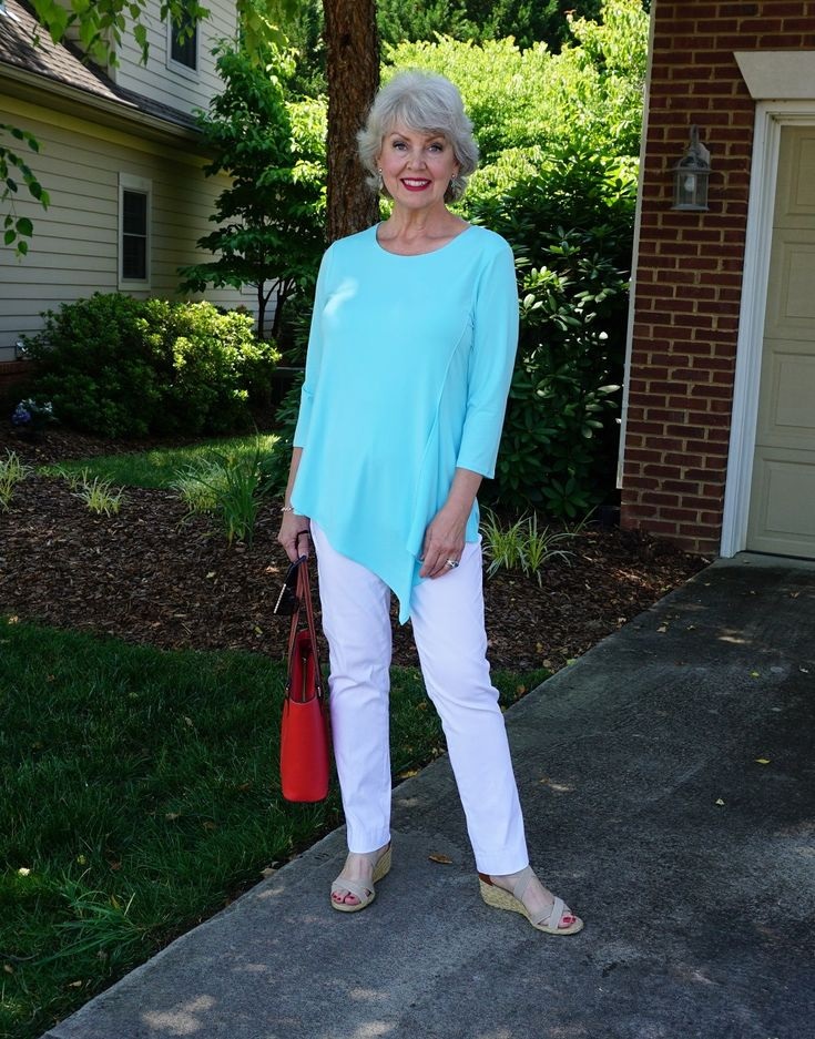 mulher de 60 anos com blusa azul e bolsa vermelha