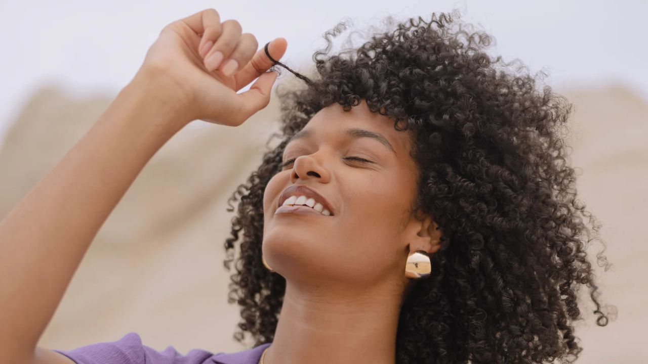 mulher mexendo em cacho de seu cabelo crespo